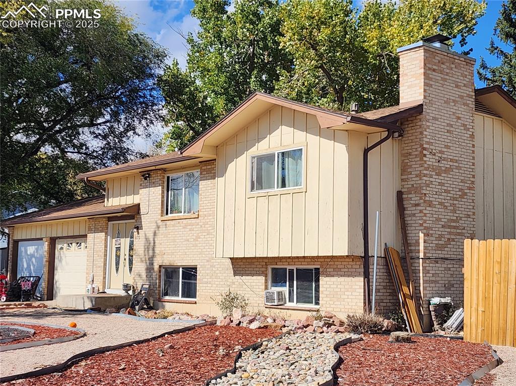Image 2 of 33: View of front of property with brick siding, a chimney, an attached garage,
