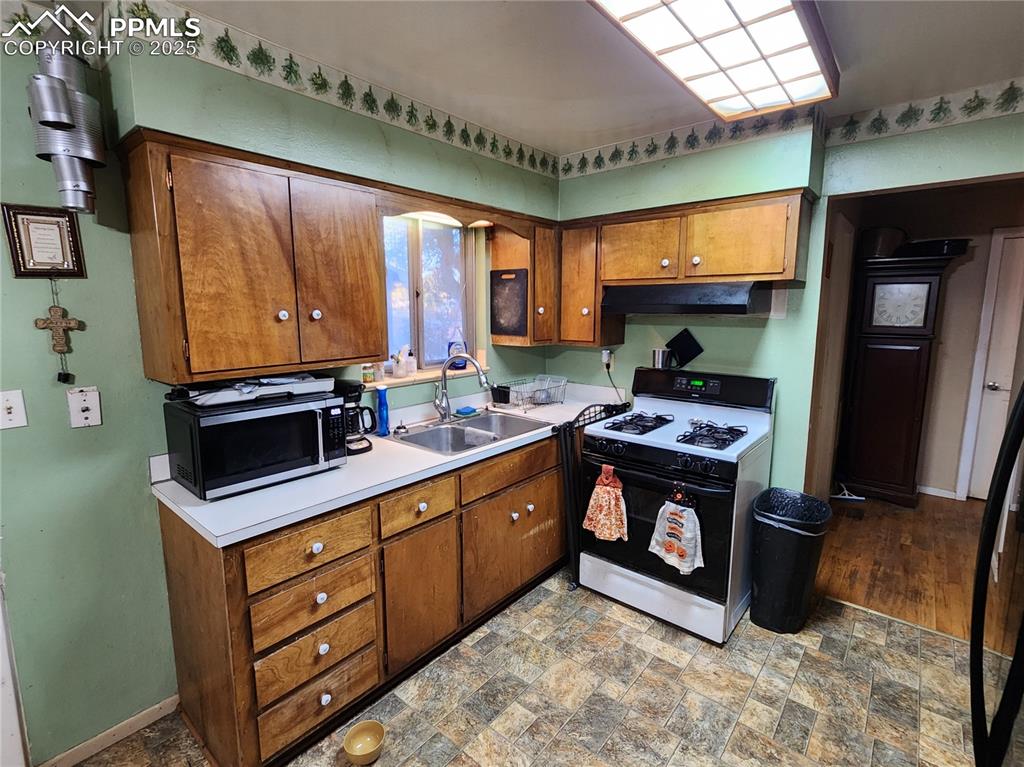 Image 8 of 33: Kitchen with gas stove, linoleum floors, light countertops