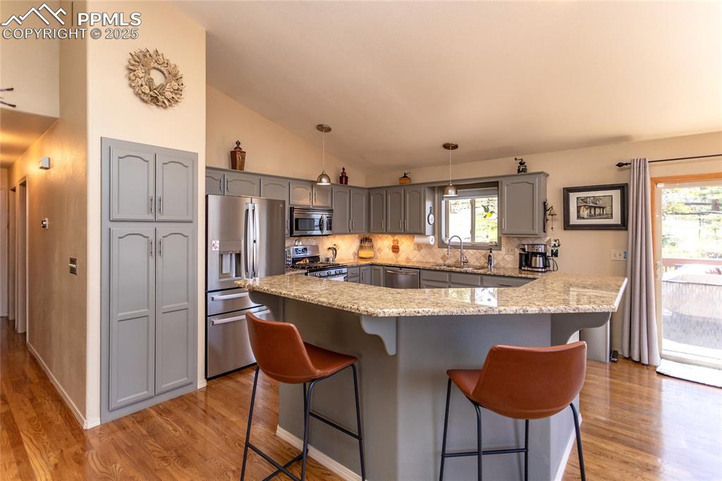 Image 13 of 44: Kitchen island with Granite counter top and walk-out to the large deck