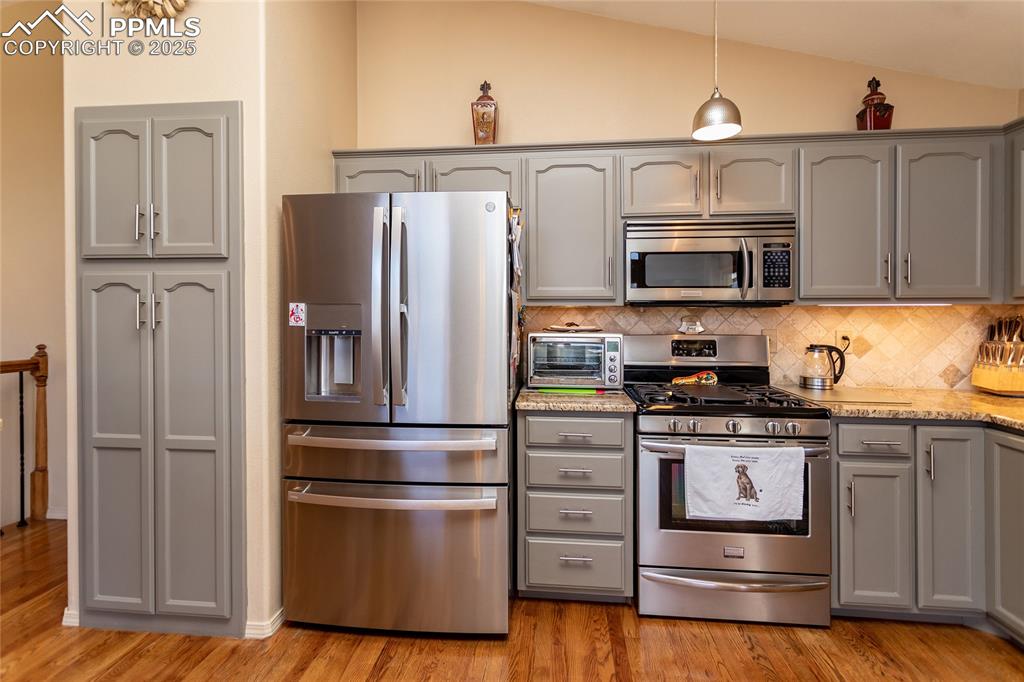 Image 15 of 44: Kitchen featuring stainless steel appliances, decorative backsplash, vaulte