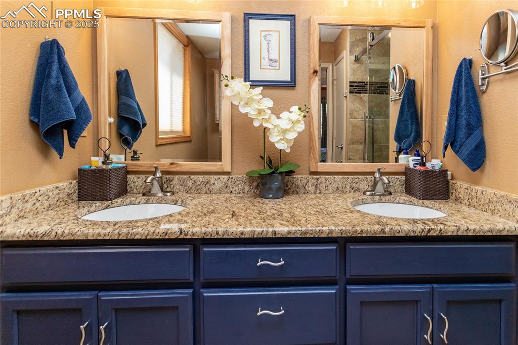Image 19 of 44: Primary bath featuring double vanity, a stall shower and granite counter to