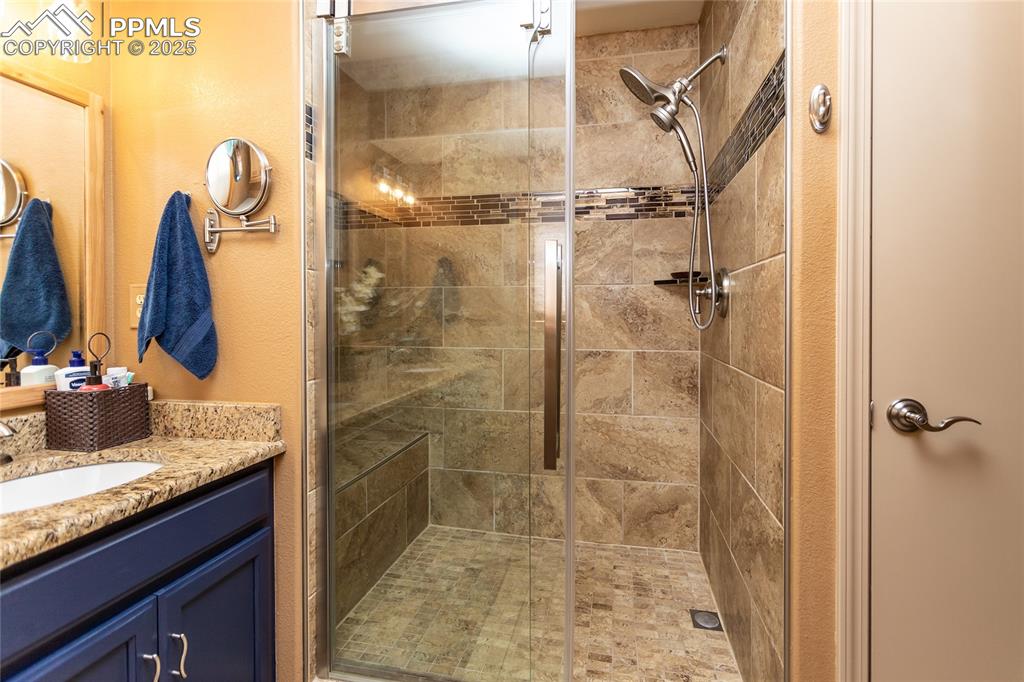 Image 20 of 44: Bathroom featuring a walk-in stall shower with bench