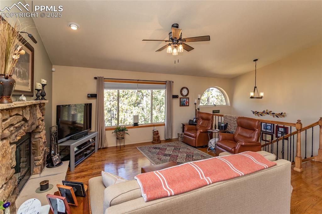 Image 9 of 44: Living area featuring a chandelier, ceiling fan, wood floors, gas fireplace