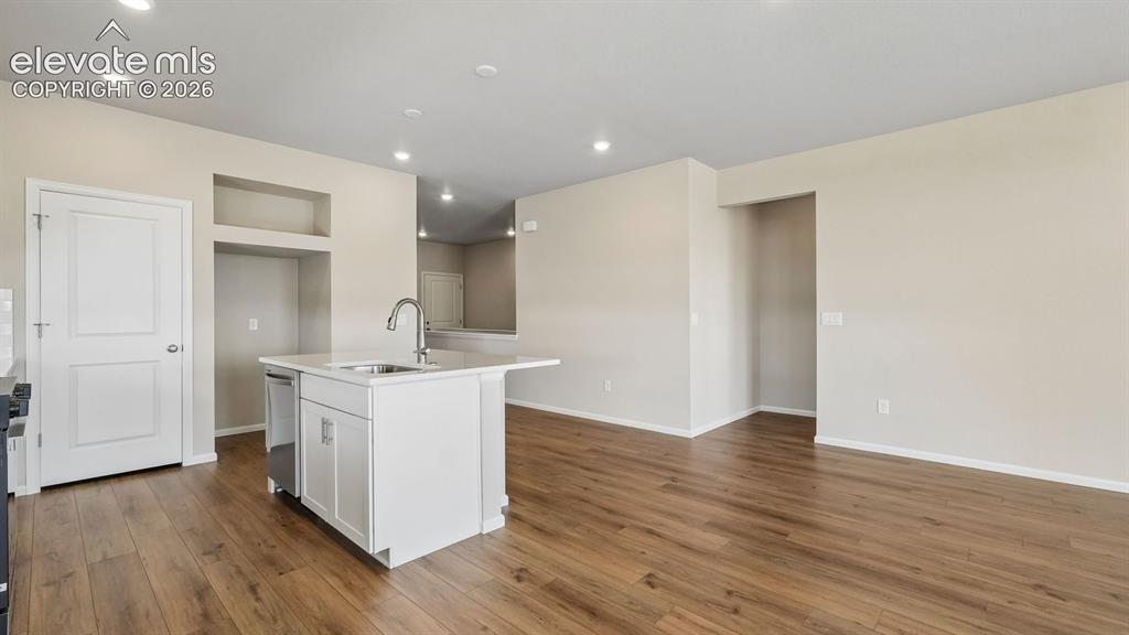 Image 10 of 47: Wood-finish flooring, recessed lighting, white kitchen island with integrat
