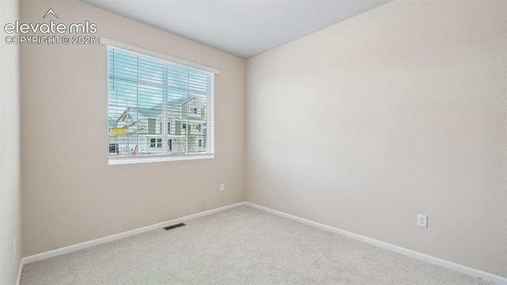 Image 15 of 47: Neutral-toned walls, light-colored carpeting, and a window with horizontal 