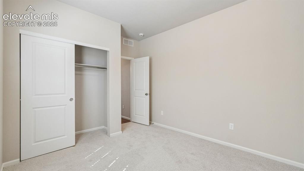 Image 20 of 47: Plush carpet flooring, closet with sliding panel doors, built-in closet rod