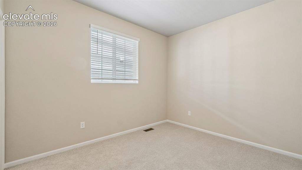 Image 22 of 47: Neutral-toned walls, light-colored carpet, and a window with horizontal bli