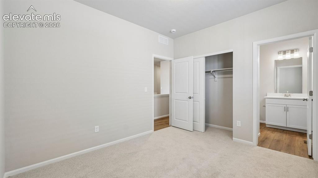 Image 24 of 47: Neutral-toned carpeting, white walls, and a sliding door closet with built-