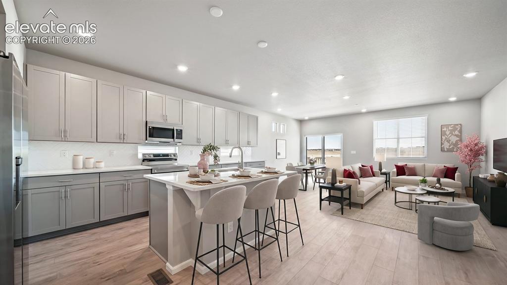 Image 3 of 11: Open-concept living space featuring wood-finish flooring, recessed lighting