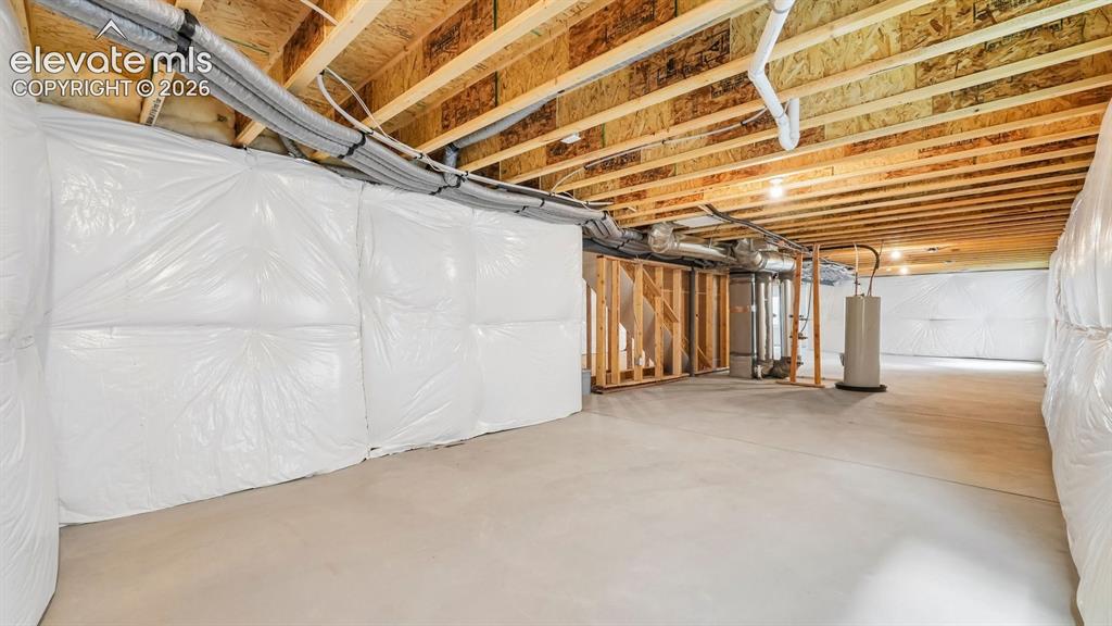 Image 36 of 47: Unfinished basement with concrete flooring, exposed wood ceiling joists, an