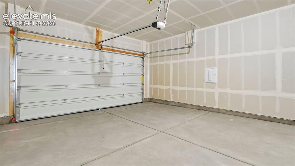 Image 39 of 47: Attached garage featuring a sectional overhead door, concrete flooring, and