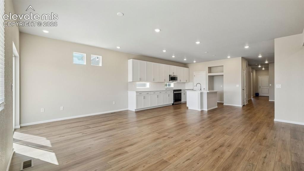 Image 5 of 47: Spacious open-concept layout with wood-finish flooring, recessed lighting,
