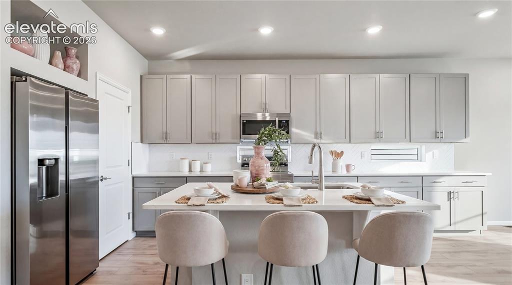 Image 6 of 11: Modern kitchen featuring a central island with countertop seating, stainles