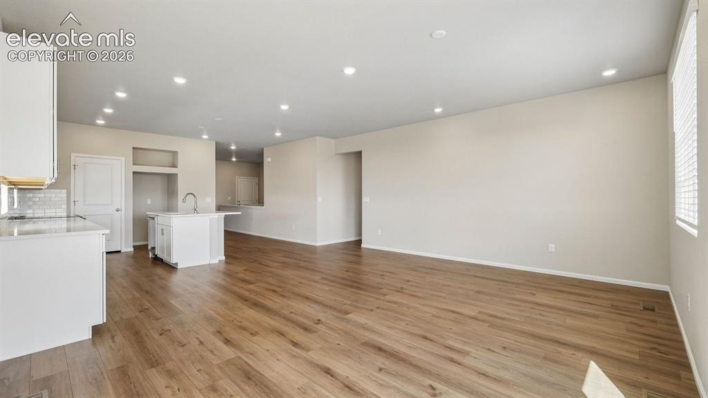 Image 6 of 47: Open-concept living area with wood-finish flooring, recessed lighting, and