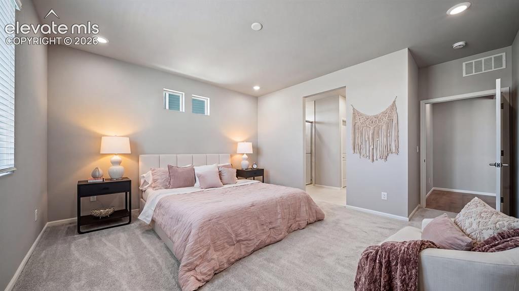 Image 7 of 11: Spacious bedroom featuring light gray walls, recessed lighting, and soft gr