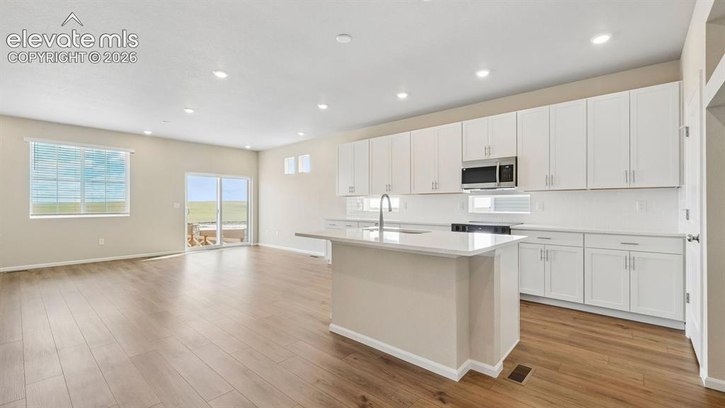 Image 7 of 47: Expansive open-concept living area featuring wood-finish flooring, recessed