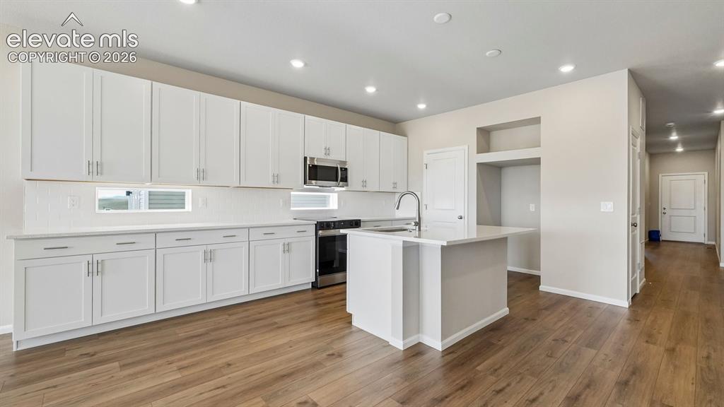 Image 9 of 47: Contemporary kitchen featuring white cabinetry, stainless steel appliances,