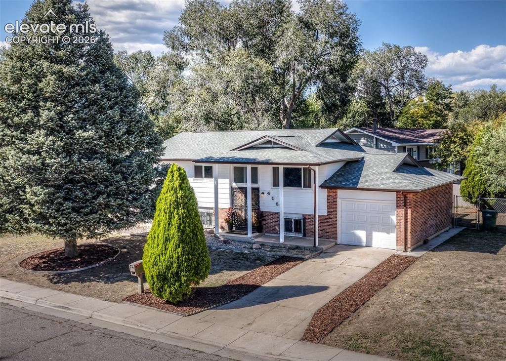 Image 1 of 48: Brick and siding exterior with a shingle roof, attached garage, and concret