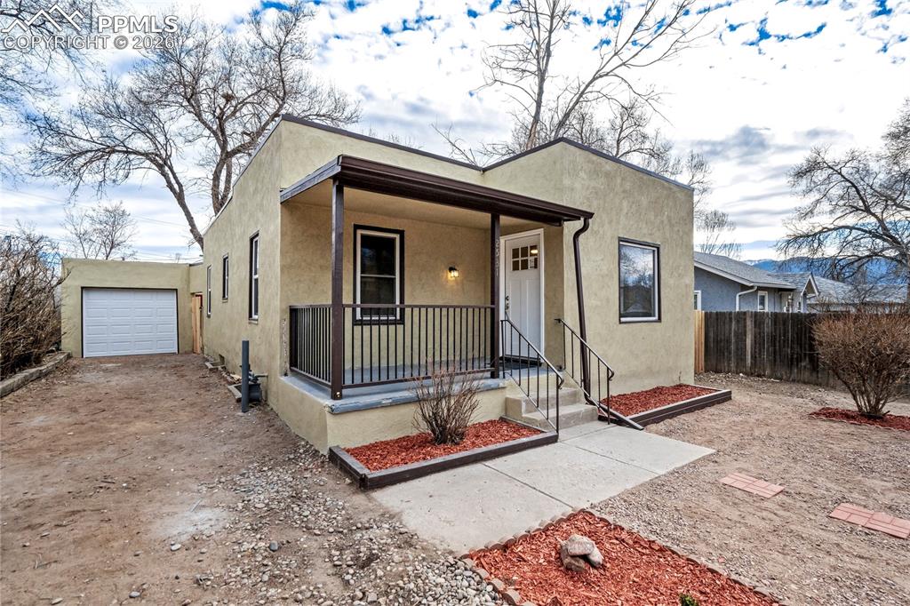 Image 1 of 28: Southwest-style home with stucco siding, front porch, gravel driveway, and 