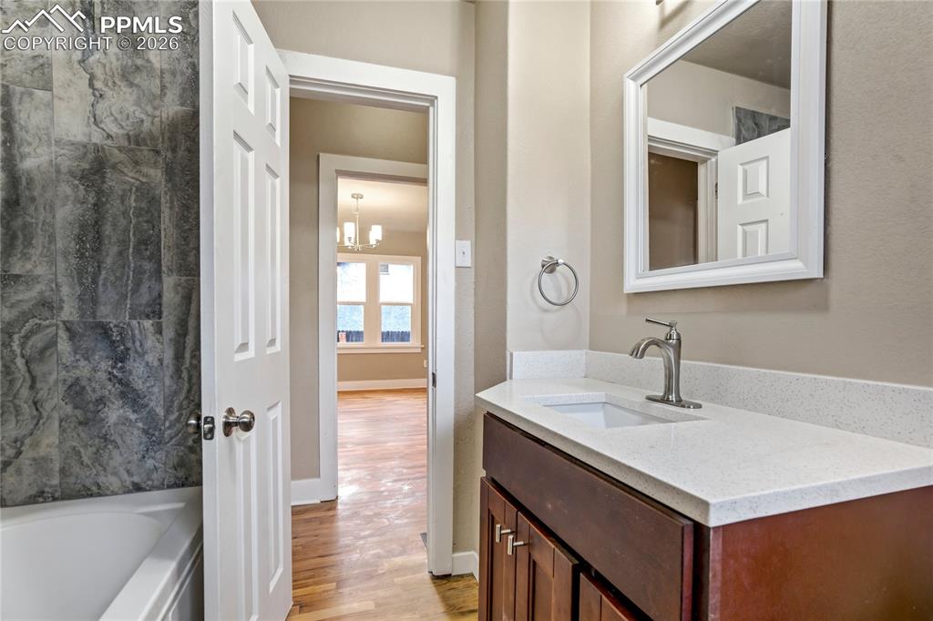Image 17 of 28: Bathroom featuring vanity, granite countertops, wood floors and a tub to re