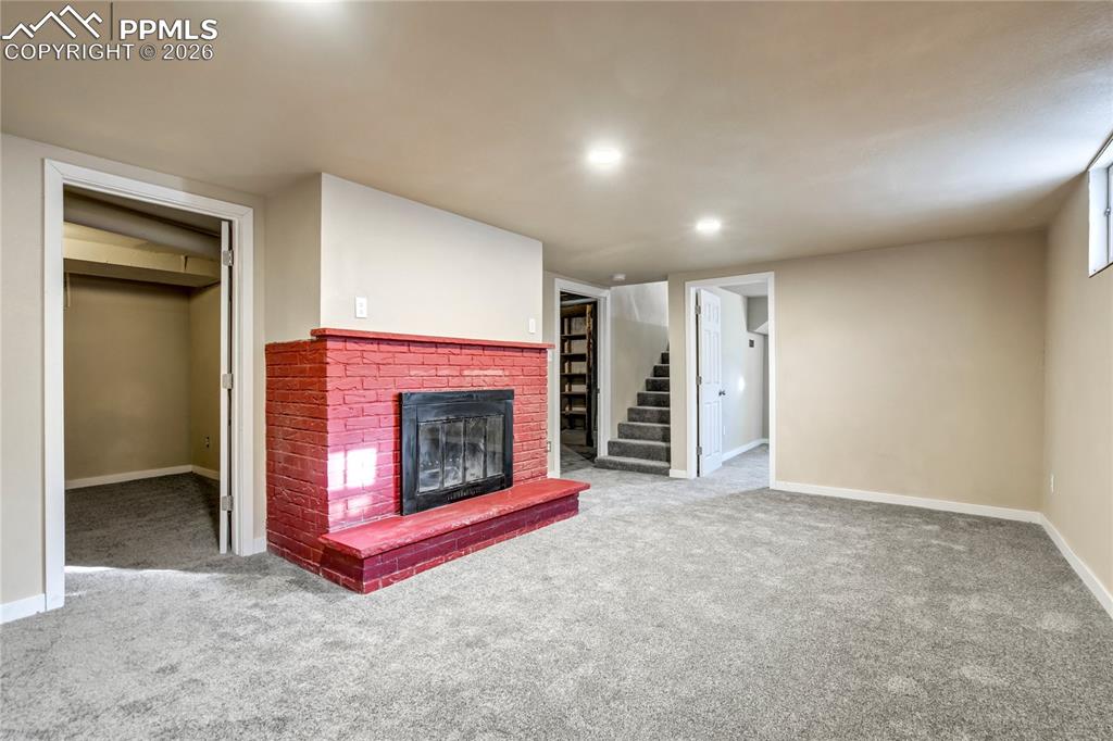 Image 18 of 28: Basement family room with fireplace, and recessed lighting.
