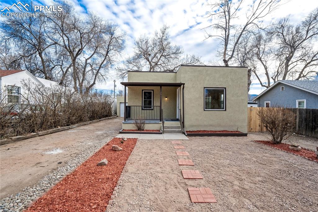 Image 2 of 28: Southwest-style home with stucco siding, front porch, gravel driveway, and 