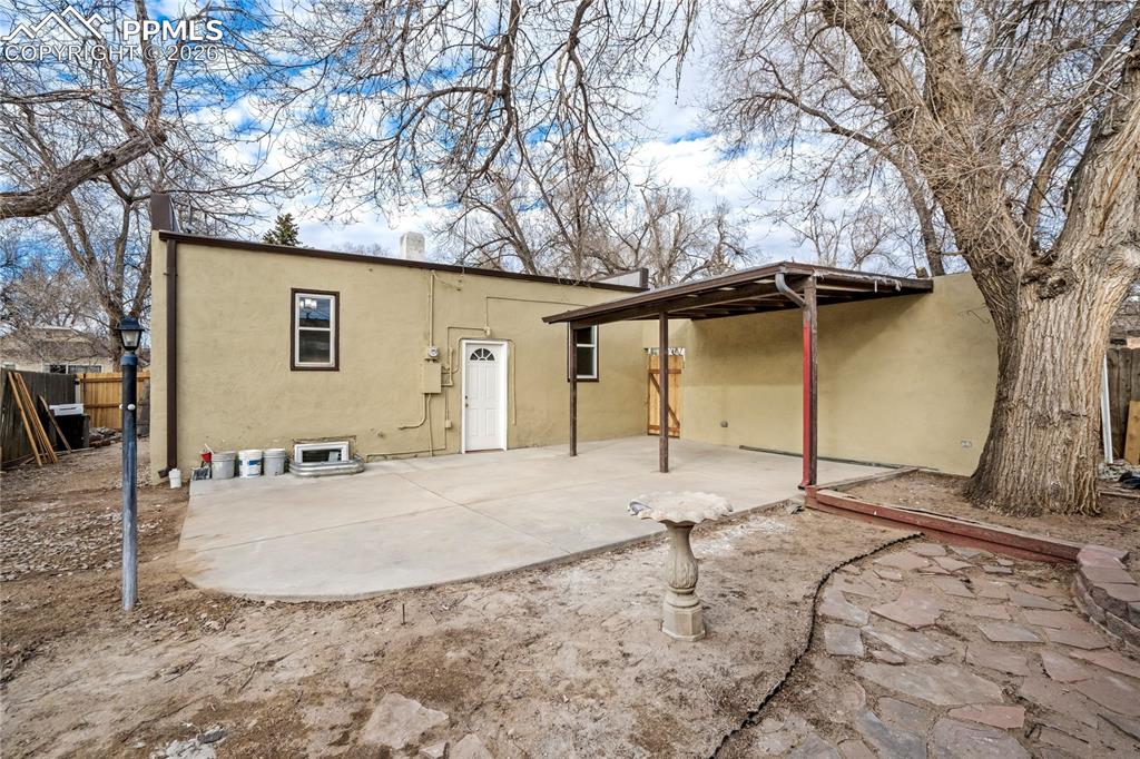 Image 28 of 28: Back of house, featuring mature trees and a birdbath