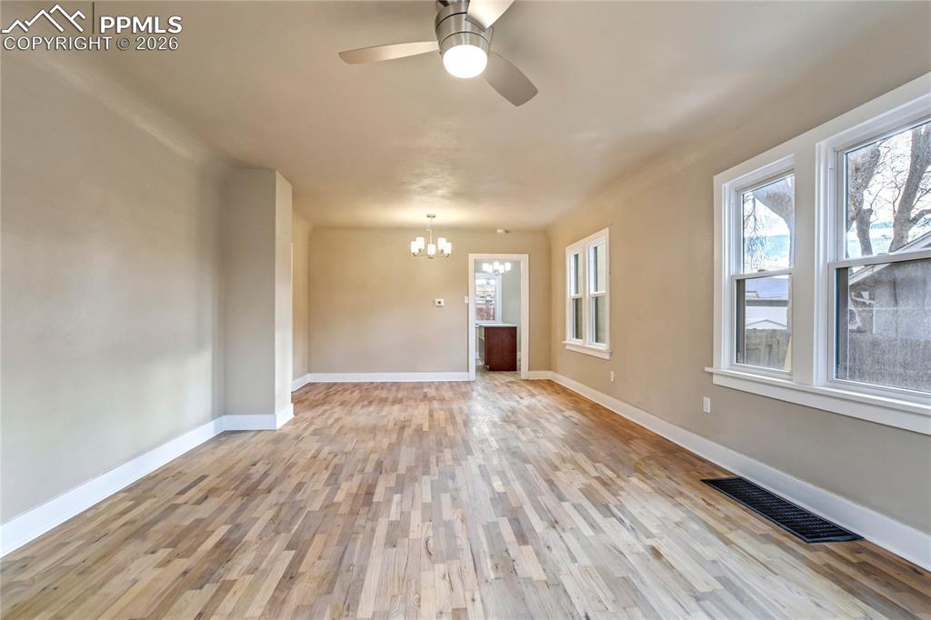 Image 5 of 28: Bright living room with wood floors, ceiling fan, chandelier, and abundant 