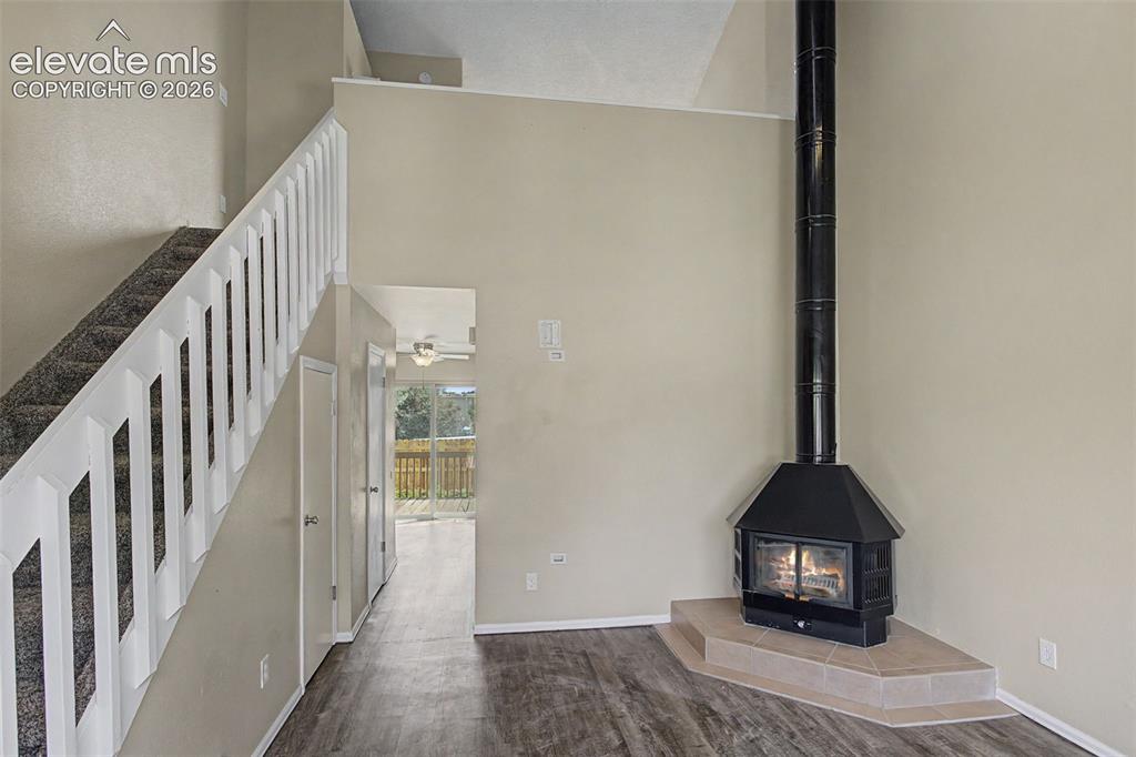 Image 7 of 26: The Living Room has vaulted ceilings, luxury vinyl flooring, and a wood bur