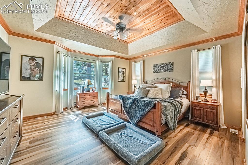Image 14 of 50: Bedroom featuring a raised ceiling, light wood-style flooring, ceiling fan,