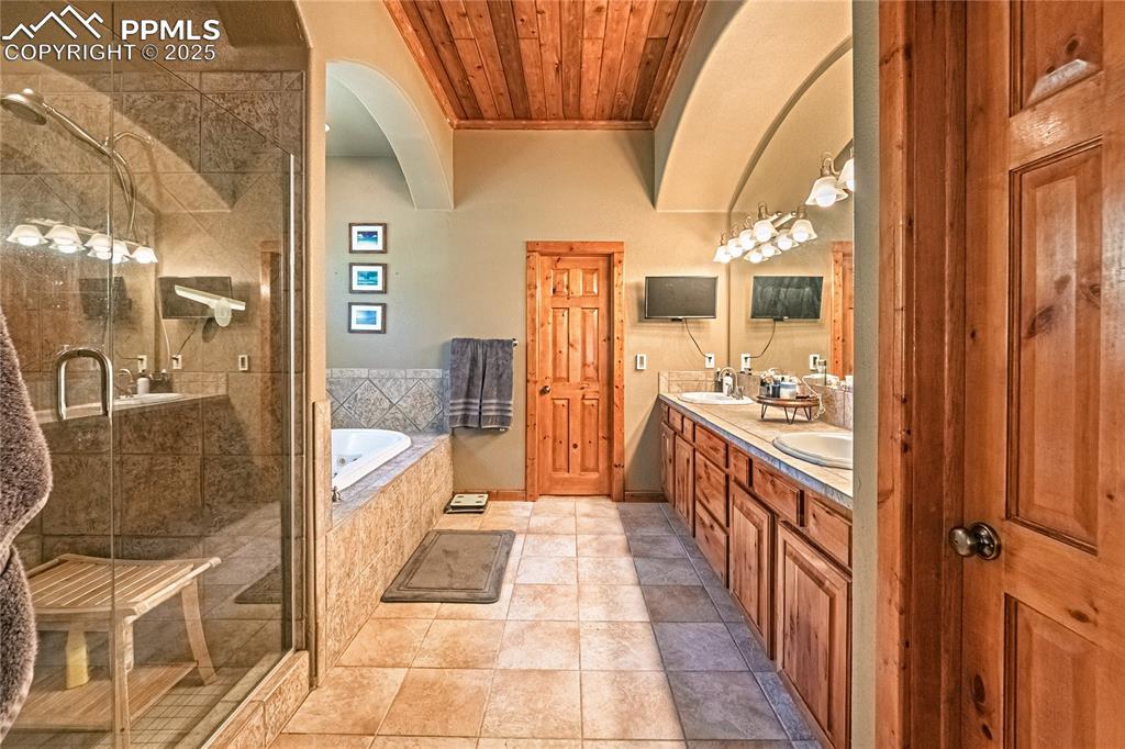 Image 16 of 50: Full bathroom featuring a bath, double vanity, a shower stall, wooden ceili
