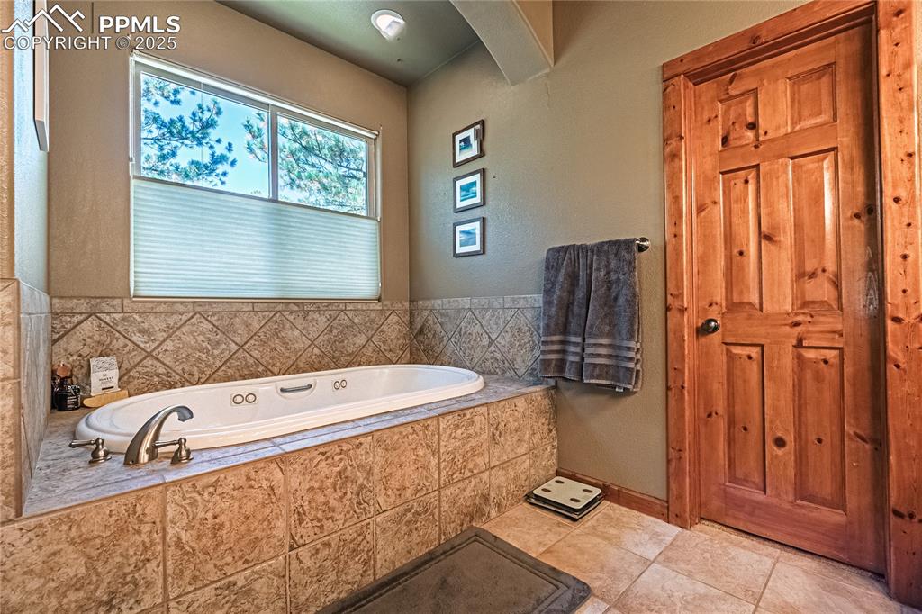 Image 17 of 50: Full bath featuring a bath, a textured wall, and tile patterned flooring