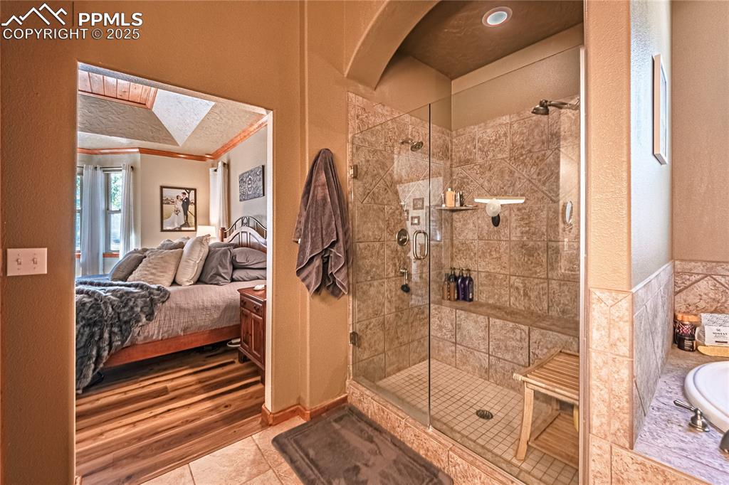 Image 18 of 50: Ensuite bathroom with a shower stall, a textured wall, tile patterned floor