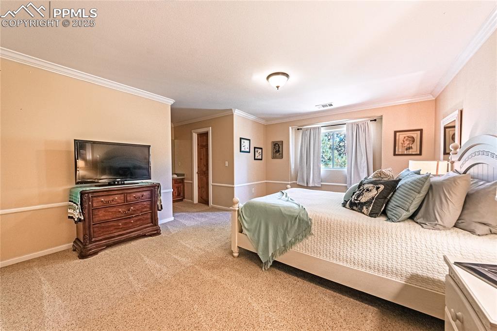 Image 27 of 50: Bedroom with crown molding and light colored carpet