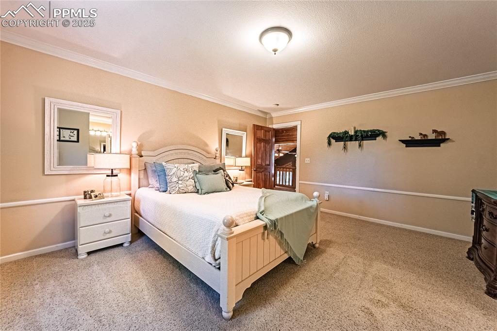 Image 28 of 50: Bedroom with light colored carpet and crown molding