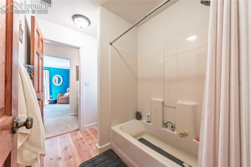Image 30 of 50: Bathroom featuring light wood finished floors and shower / bath combination