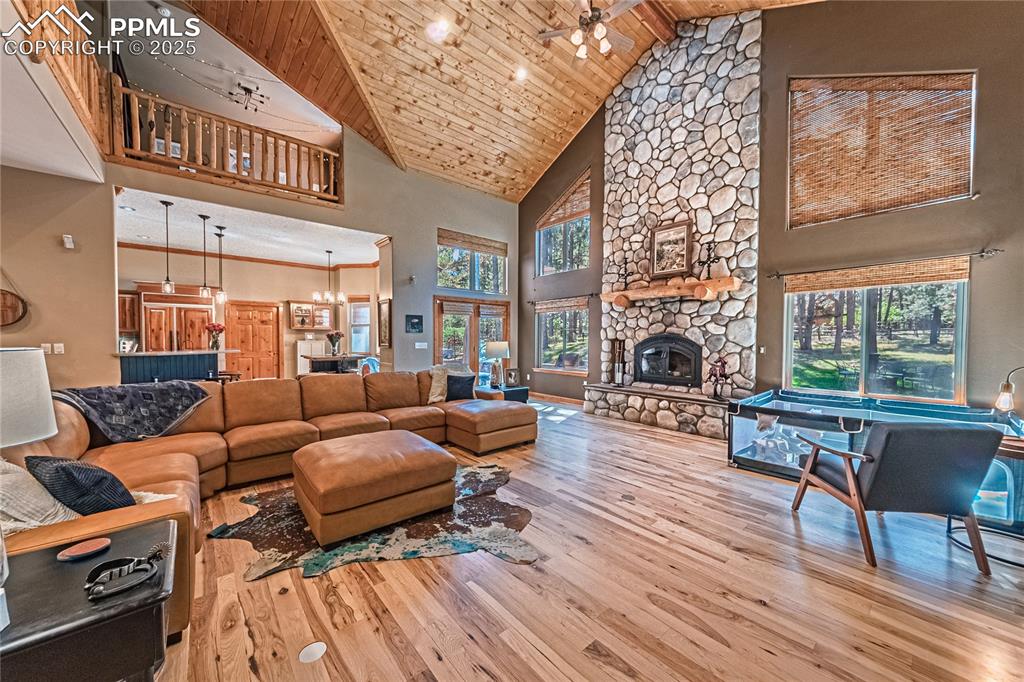 Image 4 of 50: Living area with wood ceiling, high vaulted ceiling, a stone fireplace, cei