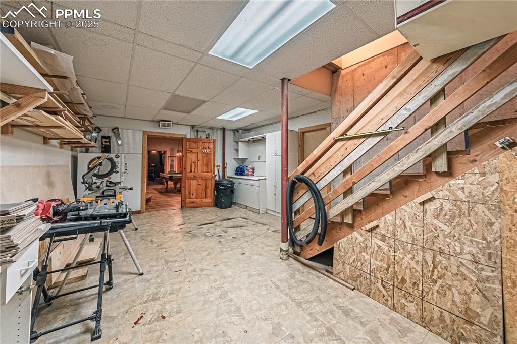 Image 47 of 50: Finished workshop on the lower level with stairs leading to the garage for