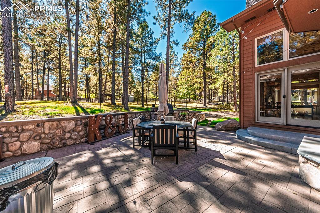 Image 48 of 50: Wooden deck featuring outdoor dining space, a patio, and view of scattered