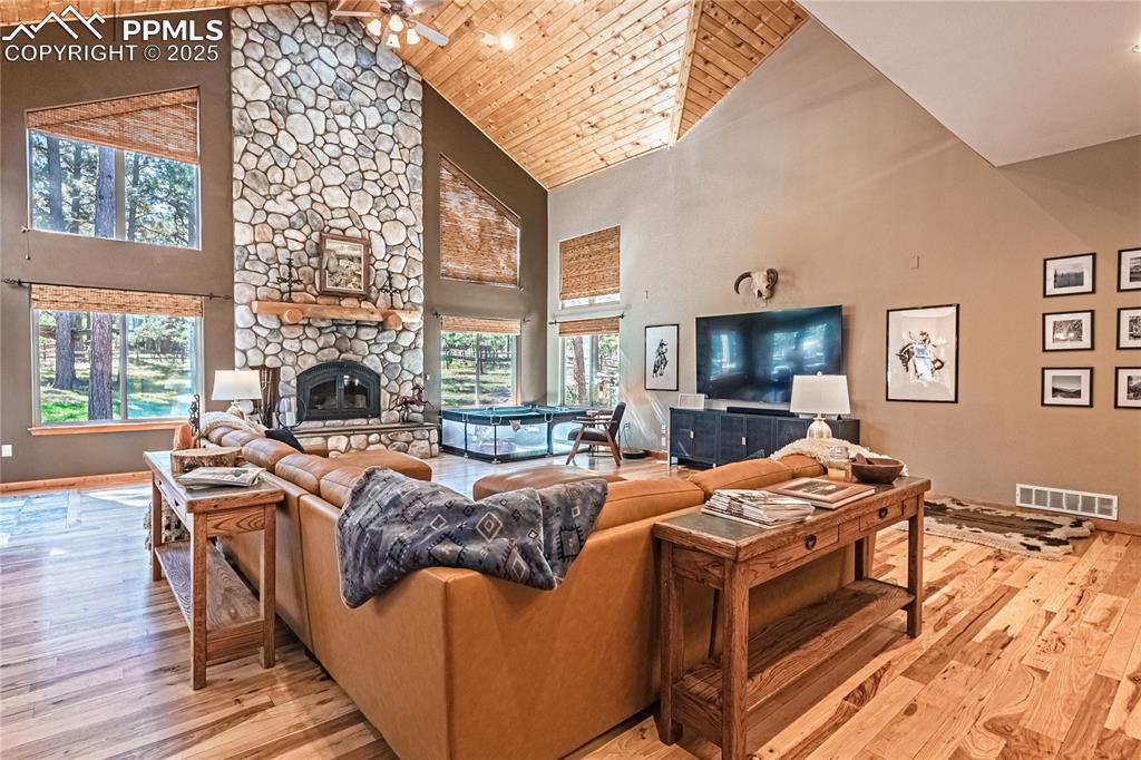 Image 6 of 50: Living room with high vaulted ceiling, a fireplace, light wood-style floori