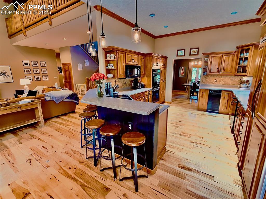 Image 9 of 50: Kitchen with a kitchen bar, open shelves, a peninsula, open floor plan, and