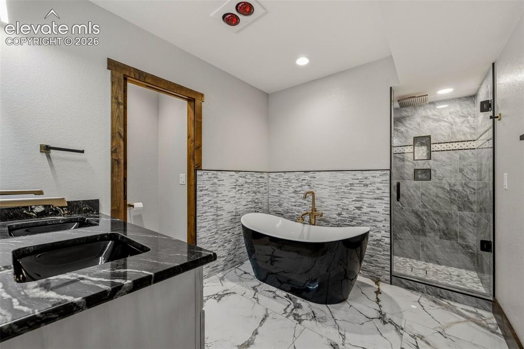 Image 34 of 46: En suite guest bathroom with dual vanities, soaking tub, and standing showe