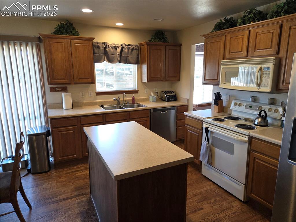 Image 13 of 38: Kitchen with stainless steel appliances, dark wood-style floors, light coun