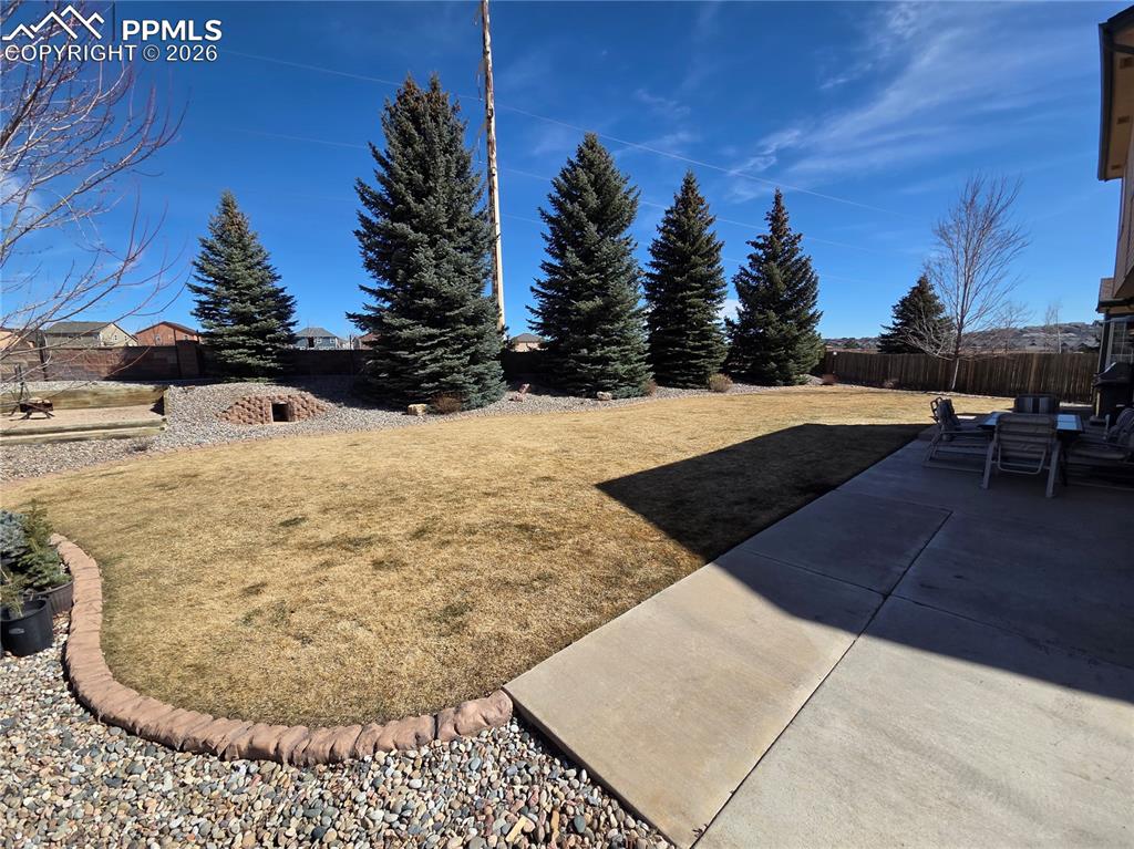 Image 16 of 38: Fenced backyard with a patio area