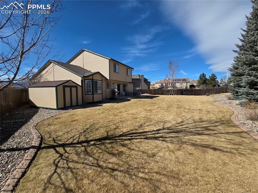 Image 18 of 38: Rear view of property with a storage unit and a fenced backyard