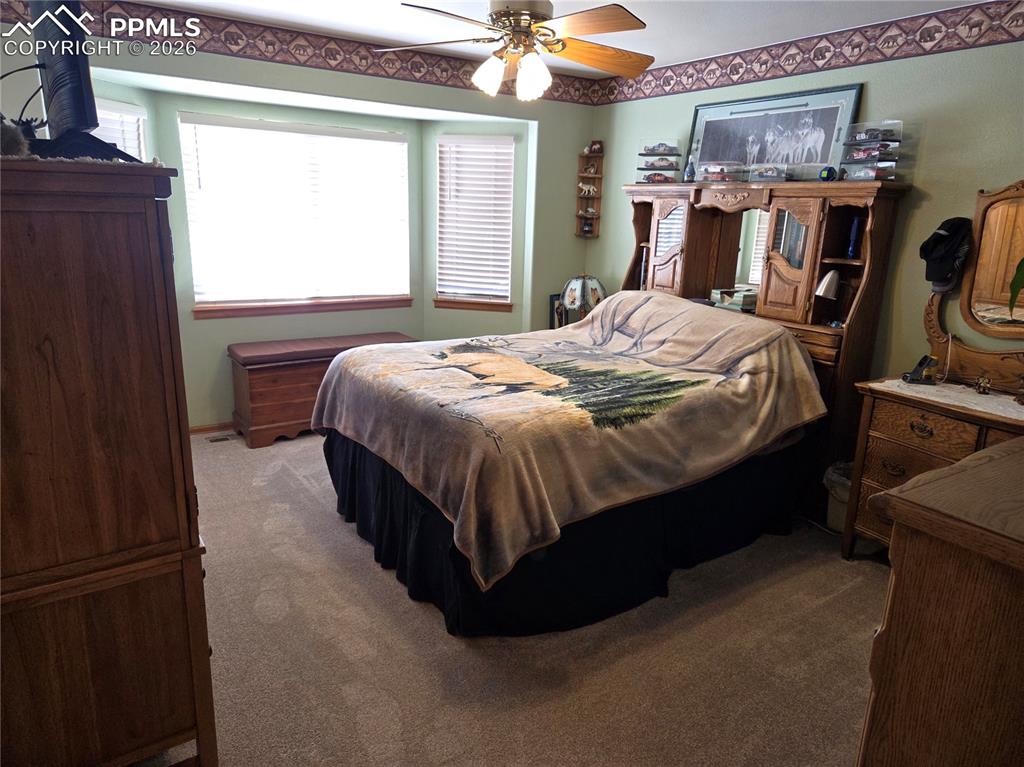 Image 20 of 38: Bedroom with dark colored carpet and ceiling fan