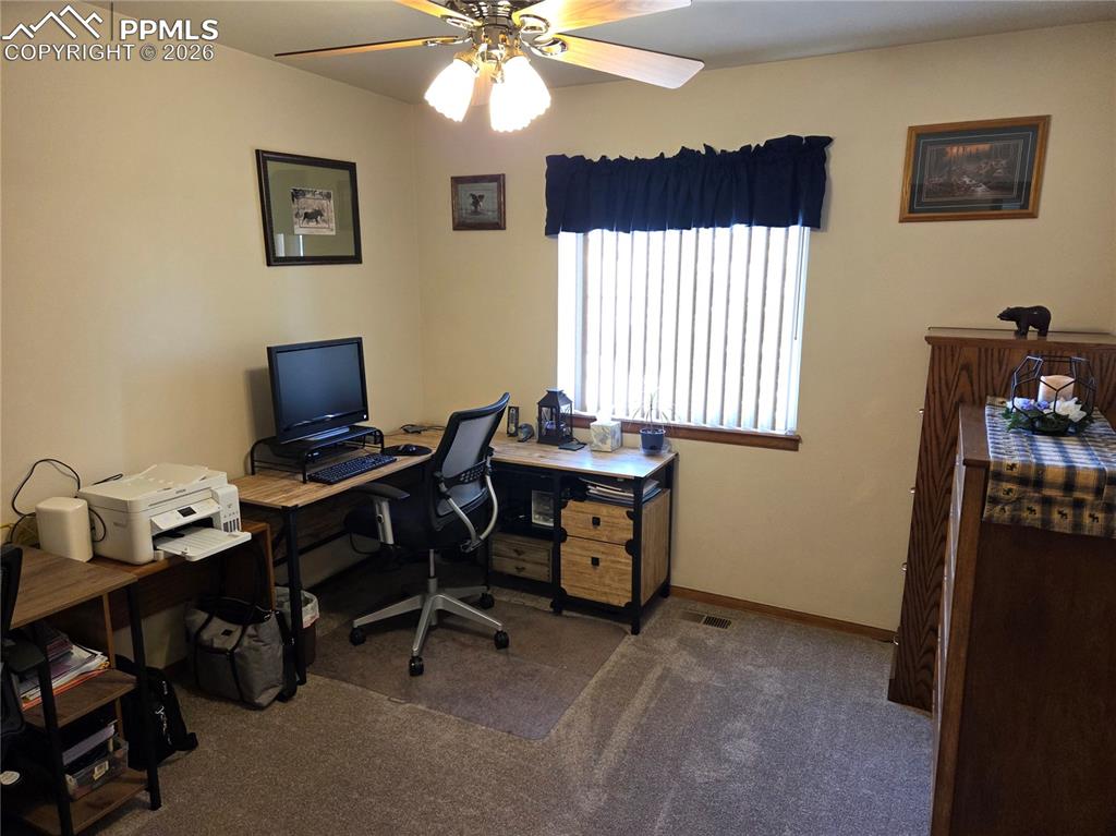 Image 24 of 38: Home office with a ceiling fan and dark carpet