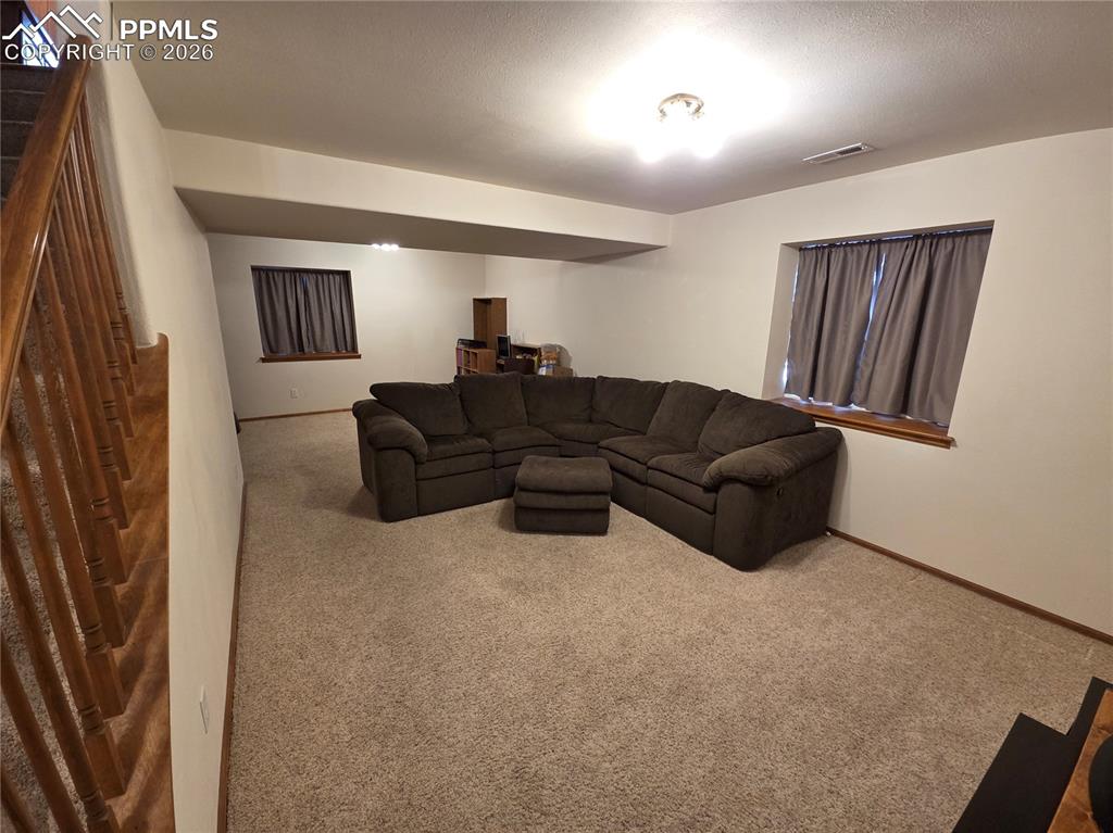 Image 27 of 38: Living room with carpet flooring and stairway
