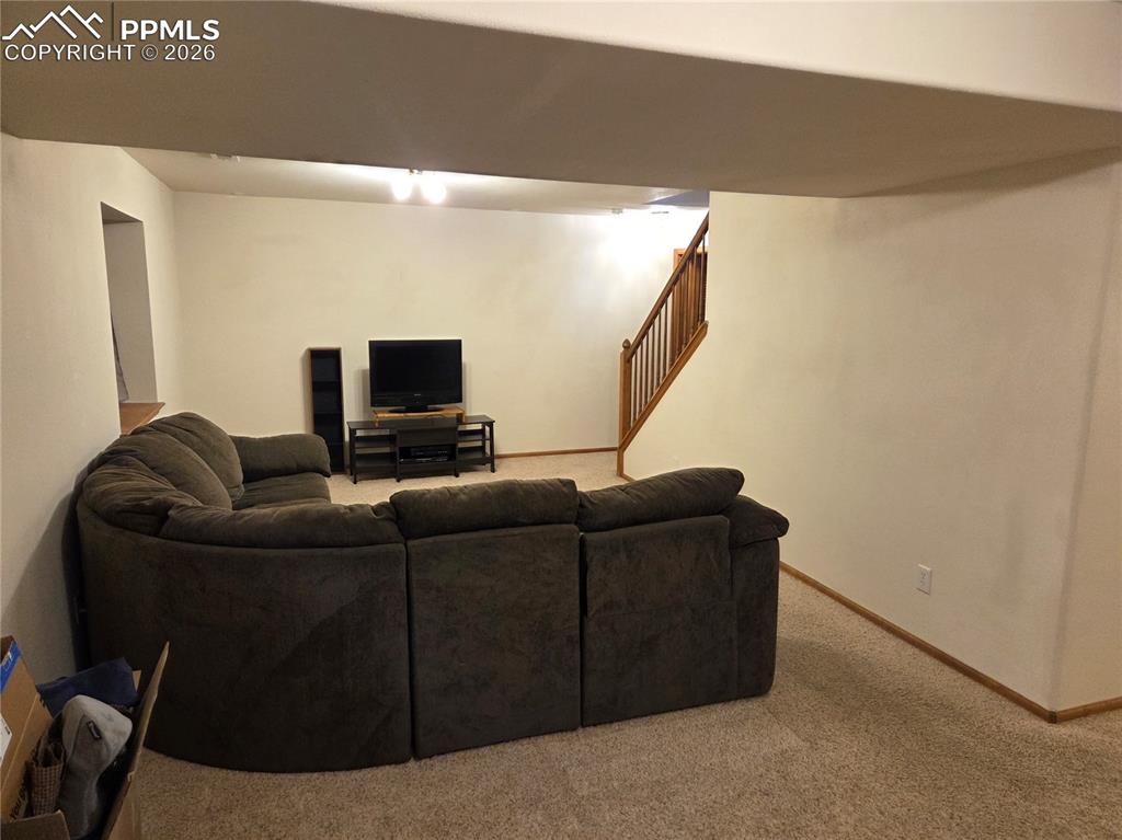Image 28 of 38: Living room featuring light colored carpet and stairs