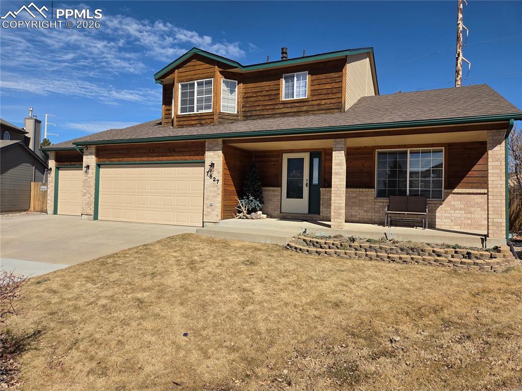 Image 33 of 38: View of front facade with covered porch, concrete driveway, a front lawn, a